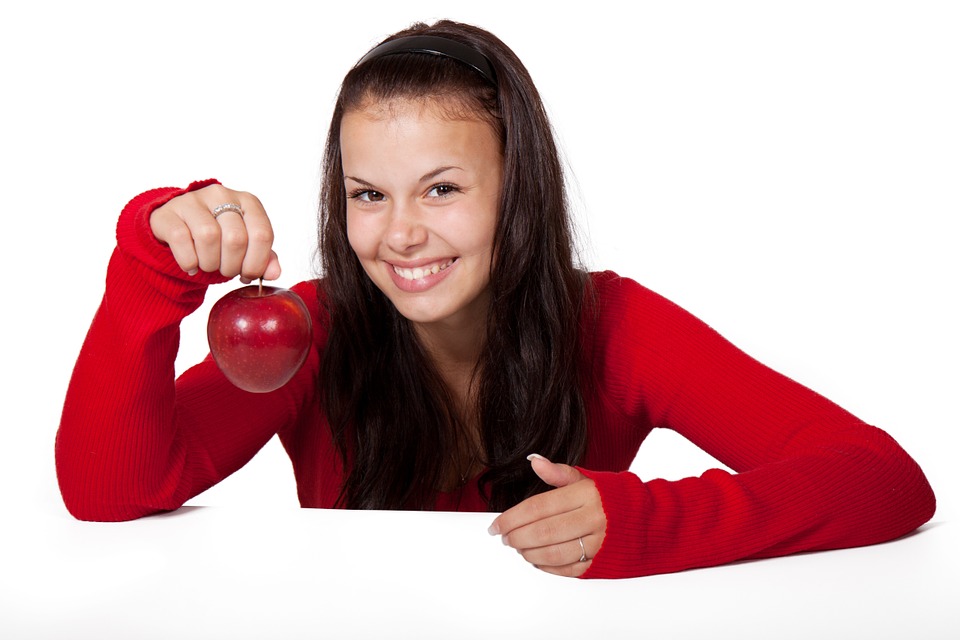 girl in red holding an apple